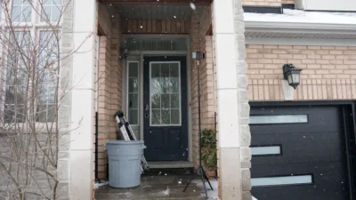 Old blue front door with a glass insert on a snowy porch in Bradford before a modern replacement.