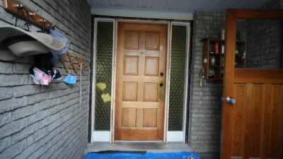 Old standard front door on a porch at Gloxinia Cres before a modern mahogany fiberglass upgrade.