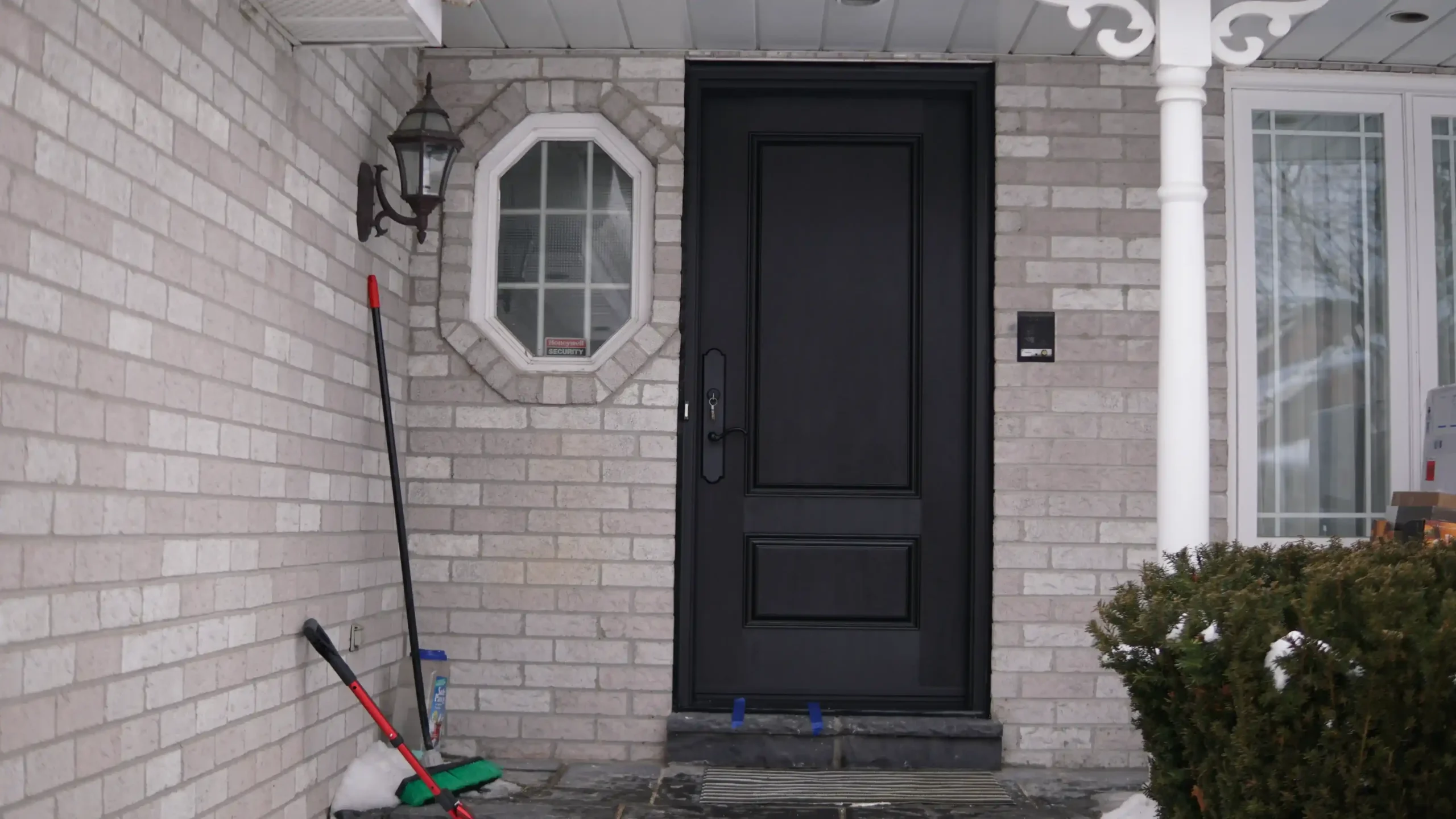 Perfectly leveled dark mahogany fiberglass entry door installed by MapleFort on an uneven porch during winter.