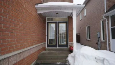 Old drafty double front doors with traditional glass on a snowy porch in Richmond Hill before replacement.